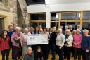 Alicia Tindal (right of centre) handing over the cheque with members of the choir