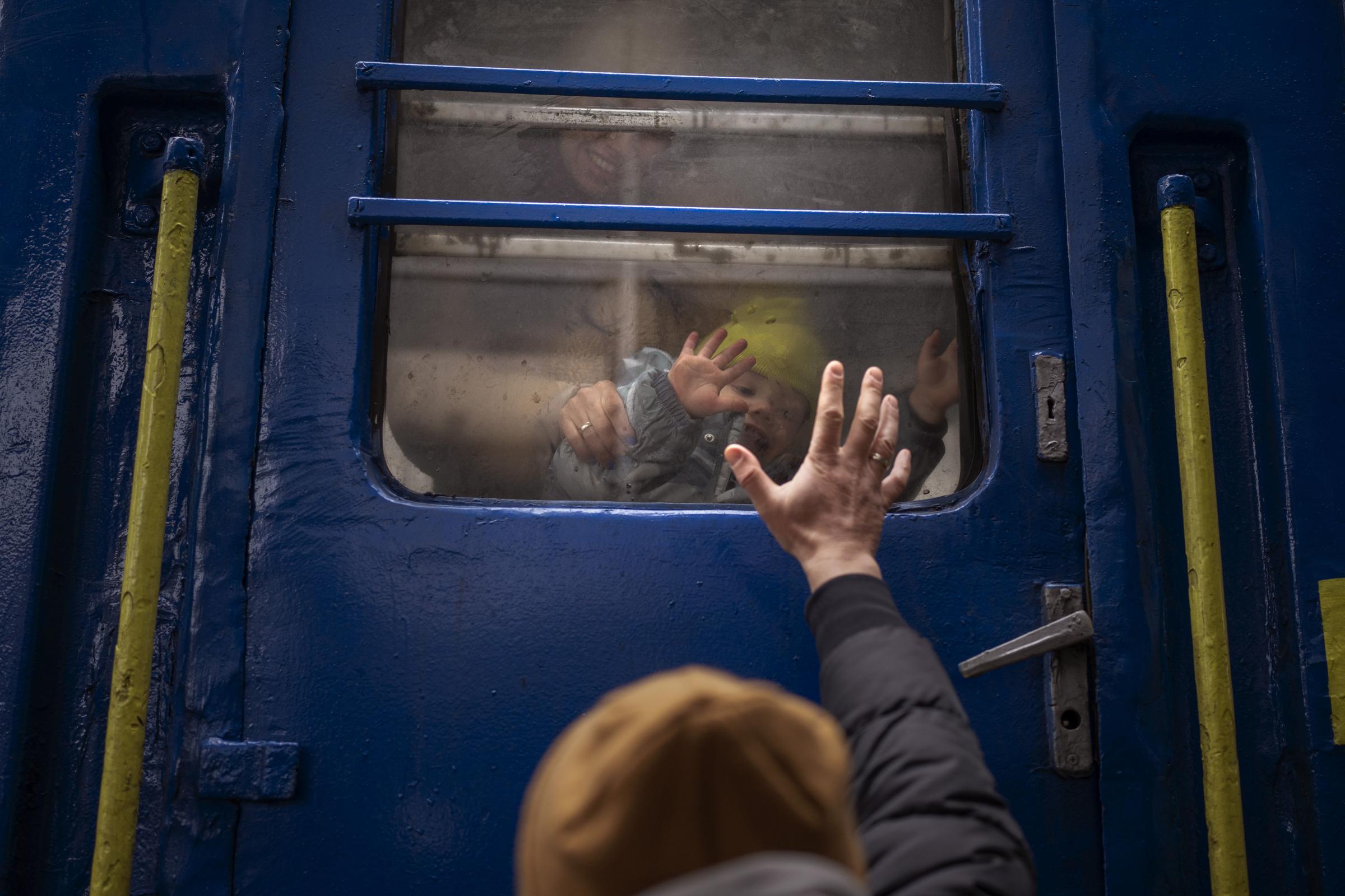 A family member waves goodbye as relatives escape to safety on a train leaving Ukraine 