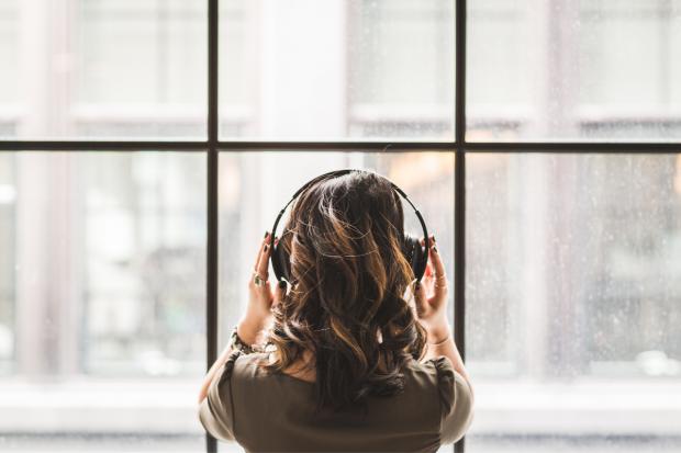 A woman listening to music on her headphoned. Credit: Canva