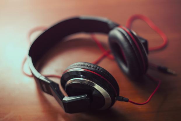 Headphones on a table. Credit: Canva