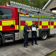 Watch Commander William Bellshaw, left, at Cove Fire Station, receives a certificate recognising 30 years